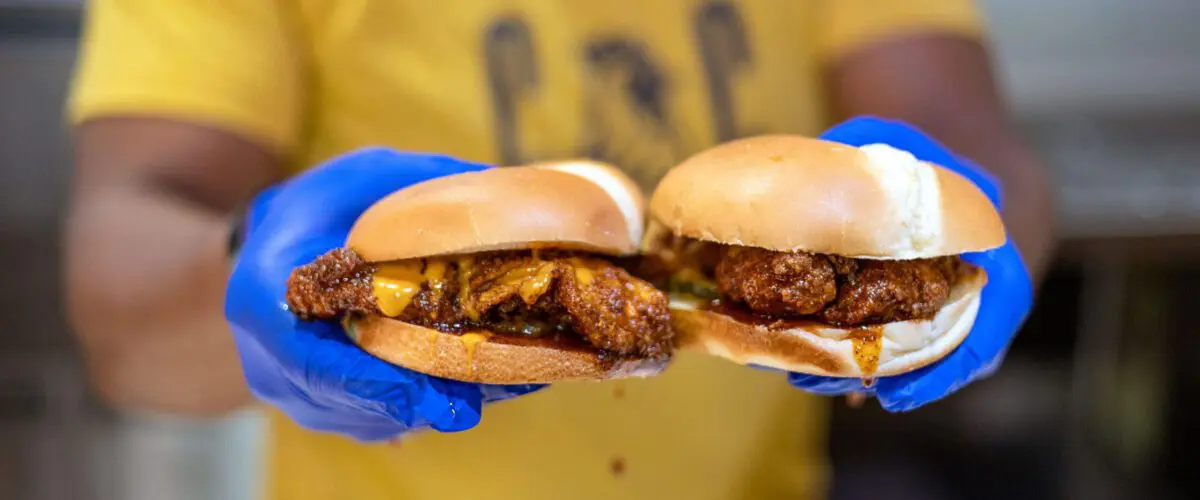 Cook holding up two chicken sandwiches