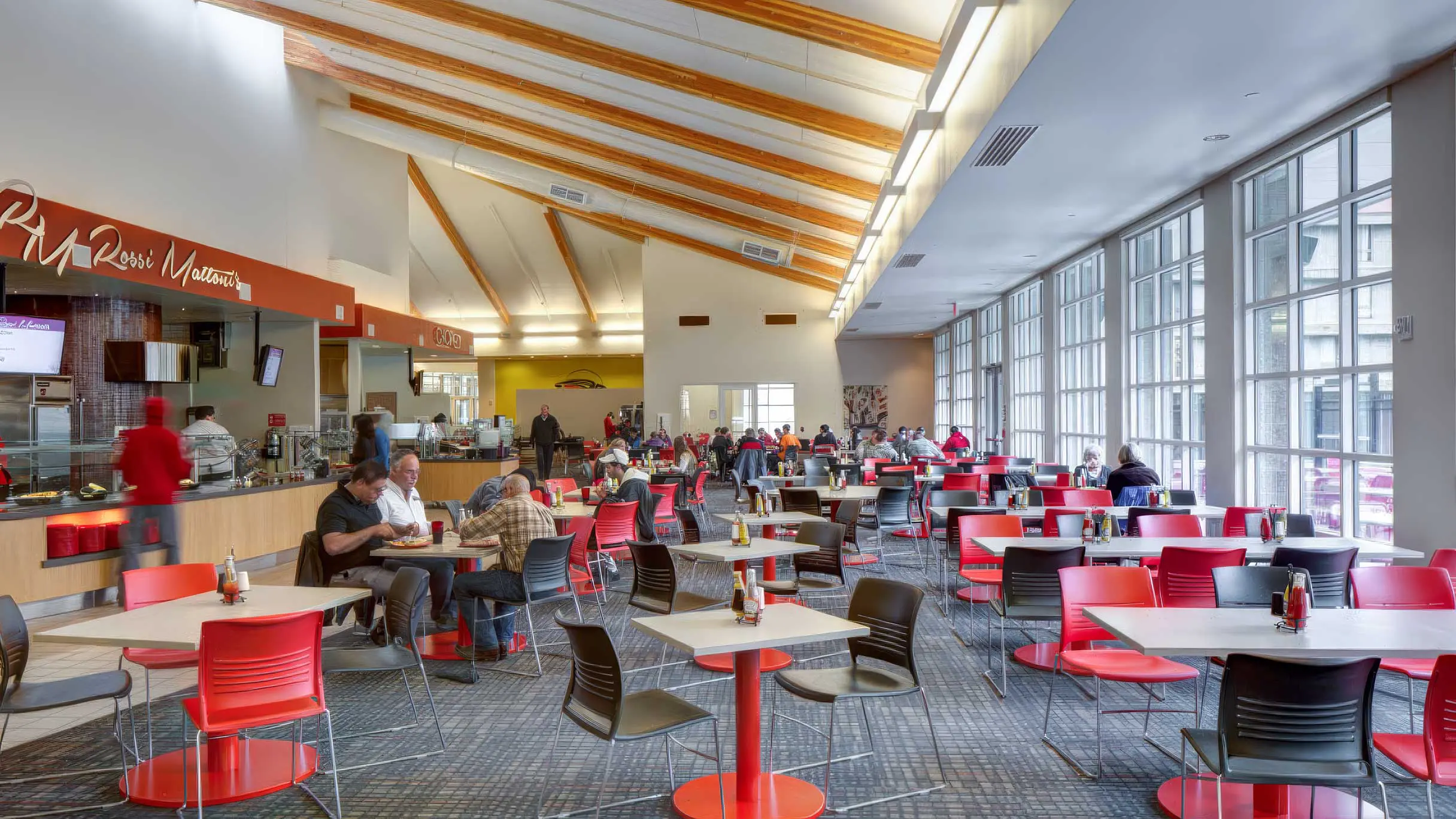 Wide view of The Hawk dining room and serving lines with patrons eating at tables