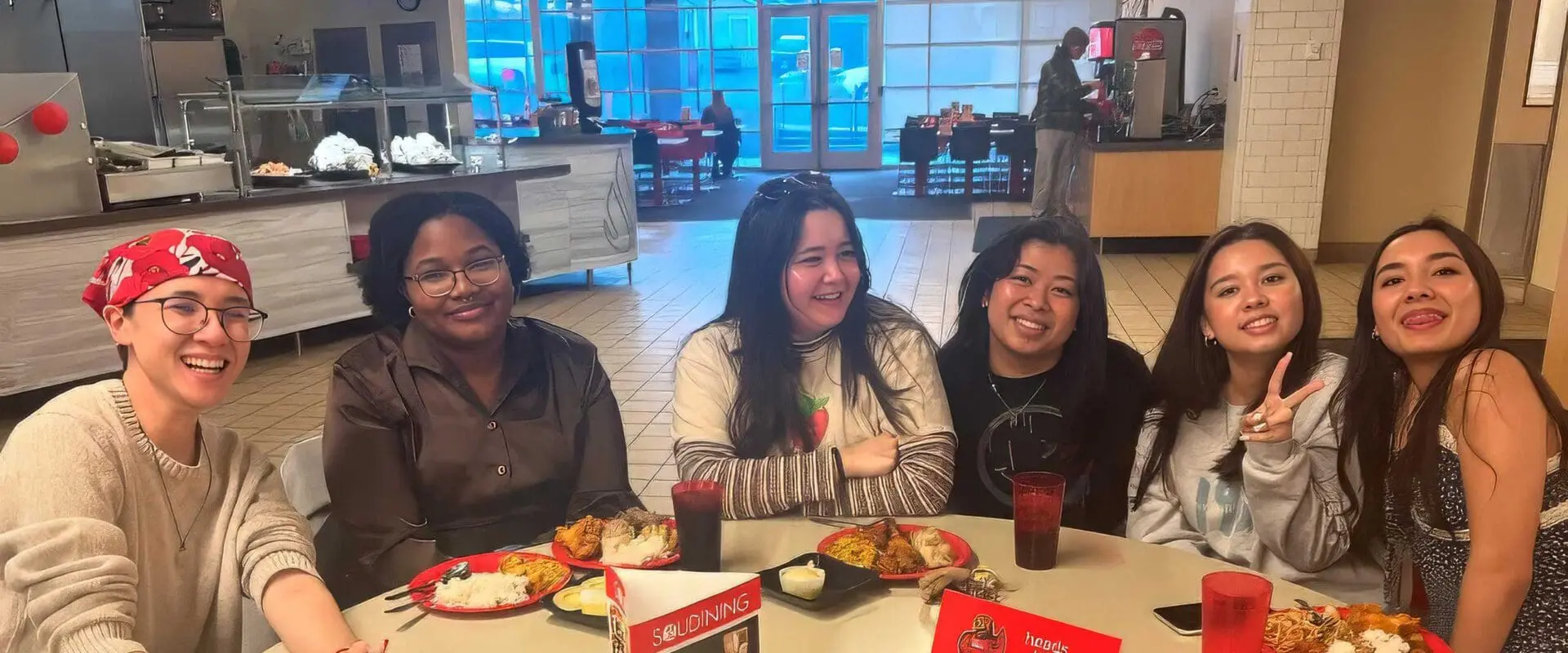 Students sitting around table at The Hawk, smiling at camera while having meal