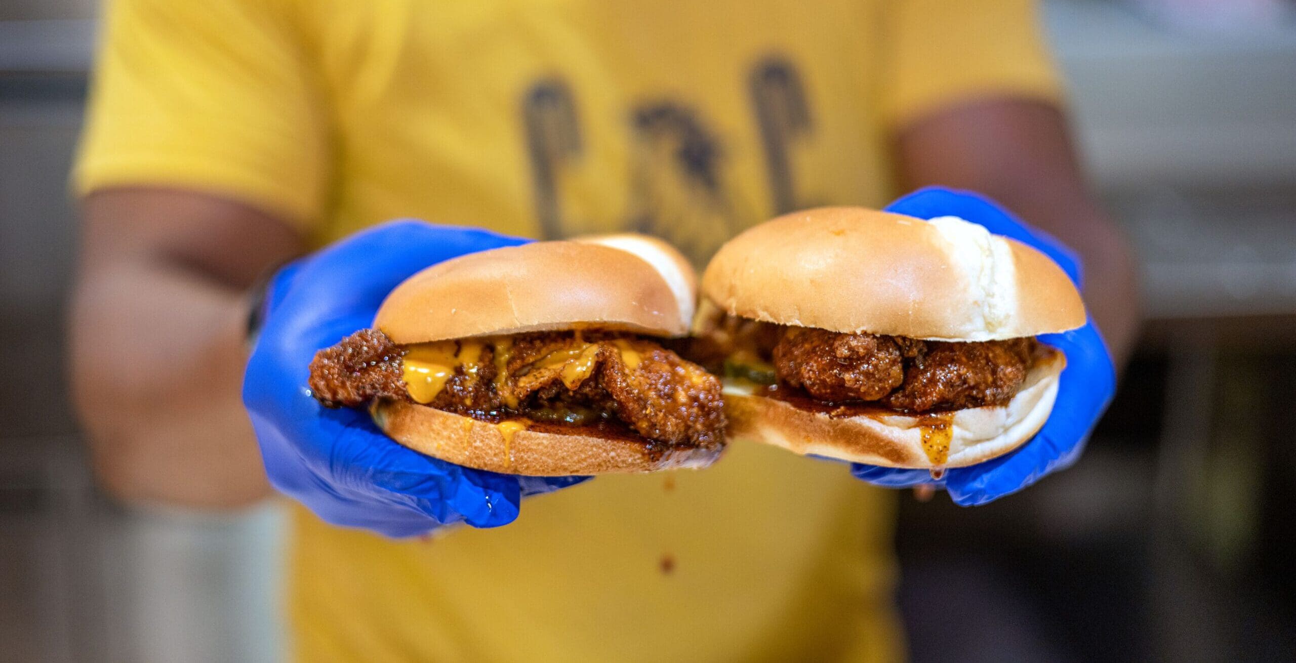 Cook holding up two chicken sandwiches